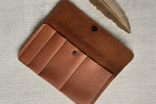Brown leather wallet on a textured beige background