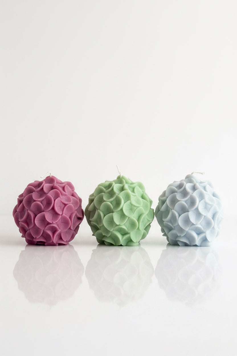Three textured spherical soy wax candles in green, purple, and light blue  on a white background